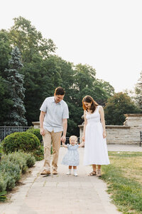 Parents and toddler daughter walking along path at Alexander Muir Memorial Gardens. Captured during their early morning family photo session by Claire Binks Photography.