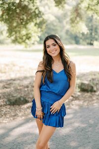 Brunette girl wearing a royal blue dress with her hands on her hips