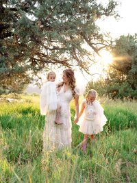 Mother walking hand‑in‑hand with her daughters through a meadow during a sunset session in Central Oregon