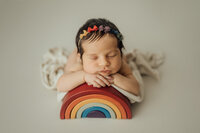 newborn baby girl posed on rainbow during photography session in Tampa