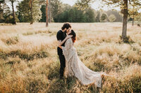 man and woman kiss in grass field at sunset