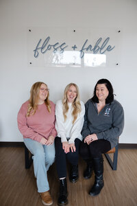 Three women standing together and smiling in a bright studio branding portrait. Photograph by Yucaipa branding photographer Kaitlyn Dawn Photography.