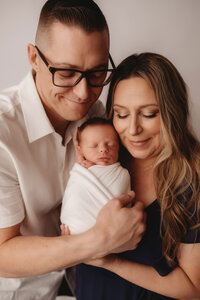 Newborn Photographer in Charleston - Parents embrace their infant during Newborn Portrait Session in Charleston, SC.