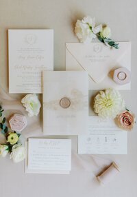 Flowers surround classic wedding invitations.