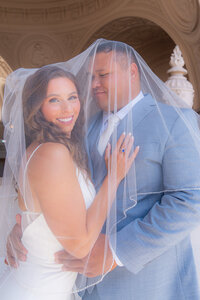bride and groom smiling under veil at san francisco city hall wedding