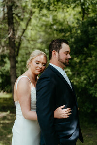 Bride embracing groom outdoors during an intimate wedding day portrait session.