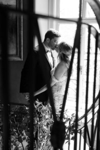 Candid black and white image of couple embracing near window light in wedding photography in Detroit