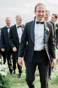 Groom walks down the aisle ahead of groomsmen