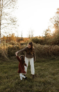 A heartwarming photo of a mom twirling and dancing with her daughter at golden hour. Fine Art New England Photographer.