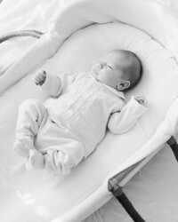 Black and white portrait of an awake newborn baby resting in a bassinet during an in-home newborn session.
