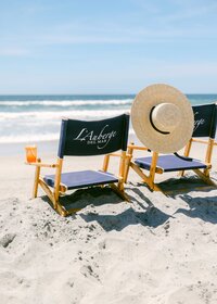 Branded L'Auberge Del Mar beach chairs with a sun hat and cocktail on the sand
