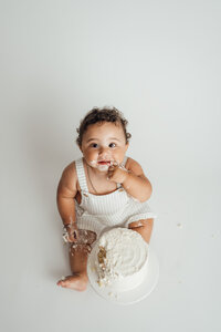 boy on white eats cake for cake smash portraits in tampa