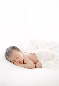 Newborn baby wrapped in cream blanket natural light home session Miami