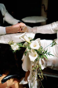 Close-up of the bride’s white calla lily bouquet as she holds hands with the groom inside Hotel Chelsea during Japna and Chris’s New York City elopement, photographed by NYC wedding photographer Perry Hancock.