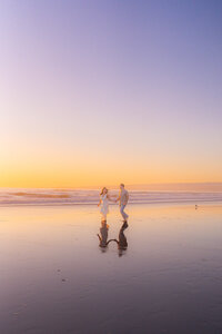 ocean couple running across santa cruz beach barefoot