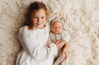 Newborn Pictures in Charleston - Siblings embrace their infant baby brother during Newborn Pictures at Holy City Babies Newborn Photography Studio in Charleston, SC.