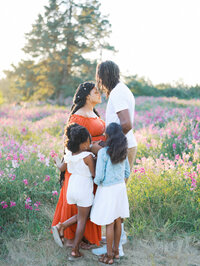 A family sharing a hug in a Discovery Park meadow