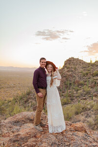 Photo of man and woman on rock surrounded by cactus