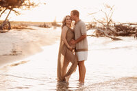 Folly Beach Maternity Photographer -- Pregnant woman poses for Maternity Photos at the Lighthouse Inlet Heritage Preserve on Folly Beach with iconic views of the Morris Island Lighthouse in the distance.