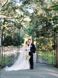 Couple standing at the gate at Legare Waring on their wedding day in Charleston SC