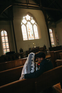 bride and groom sharing a kiss in a church pew in pensacola florida