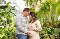 Man and woman posing for maternity photographyy in oakland county michigan greenhouse
