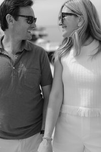 Couple hold hands while sitting on dock on Nantucket.