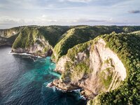 Aerial view of green cliffs over dark blue ocean