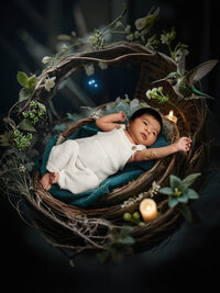 4Karma Studio - A whimsical fine art newborn portrait of a baby in a handwoven basket reaching for a hummingbird, featuring creative composite artistry in Los Angeles.