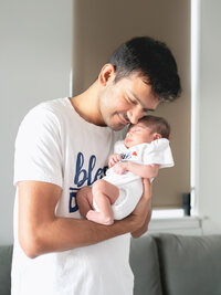 Los Angeles newborn photography intimate moment of a dad holding his newborn with soft natural light and a warm lifestyle documentary feel.