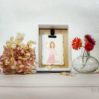 framed mini portrait of little girl wearing pink dress with dried hydrangeas and a small bud vase  with white background