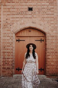 Creative branding portrait of Sharni Tolhurst standing under a brick archway.