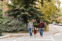Dads and their daughter walking through their toronto neighbourhood during their family portrait session
