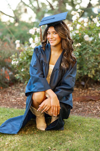 High school graduate posing outdoors in a blue cap and gown during golden hour, senior photography by Kaitlyn Dawn Photography.