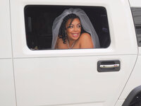 An African-American bride smiles from the limo in SF