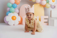 Cake Smash Photographer in Charleston, SC - Baby smiles at the camera during Cake Smash Photoshoot at Holy City Babies in Charleston, SC.