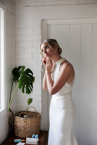 Bride getting ready near window in natural light