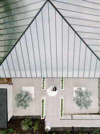 A striking overhead view of a modern glass-roofed wedding venue, highlighting refined composition and intentional imagery from a unique perspective.