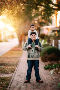 Older brother holding younger brother on his shoulders during a New Bern family session