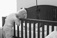 Professional photography by Nature's Child Photography: St. Augustine newborn capturing a black and white moment as a big brother rests his arms on the crib and studies his sleeping baby brother.