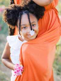 A little girl peaking from her mom's dress during a maternity session in Discovery Park in Magnolia, Seattle