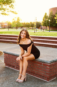 Senior girl wearing black dress sitting on the bench outside of MTSU library
