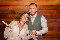 Bride and groom posing together for a formal portrait in front of a rustic wooden barn wall