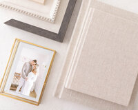 close up photo of album and frame products with couple looking at eachother