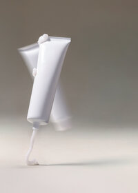 Studio still of a white product tube against a soft grey background