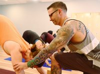 Male yogi giving hands on adjustment to student