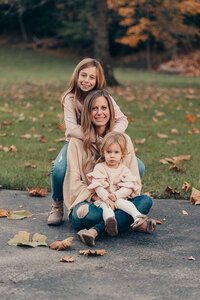 Mother sitting with her two young children on fallen autumn leaves during a Cleveland family photography session