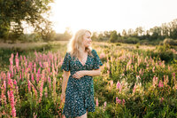 Branding fotografie van jonge vrouw in jurk in een bloemenveld met tegenlicht