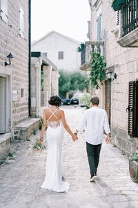 bride-groom-are-walking-holding-hands-along-narrow-street-ancient-town-back-view