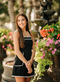 Senior portrait in downtown Foley, Alabama — wearing a black dress with flowers in the background.